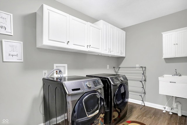 laundry area with washing machine and clothes dryer, a sink, baseboards, cabinet space, and dark wood finished floors