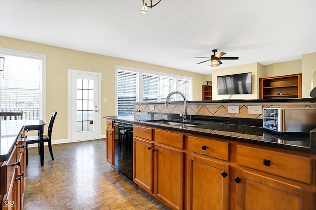 kitchen featuring a sink, backsplash, dishwasher, brown cabinetry, and dark stone countertops