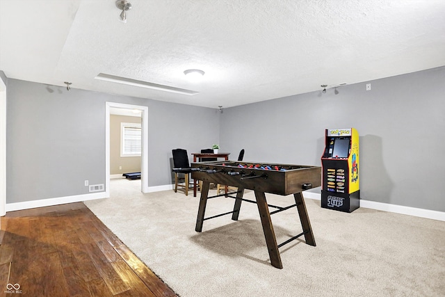 rec room featuring a textured ceiling, carpet flooring, and baseboards