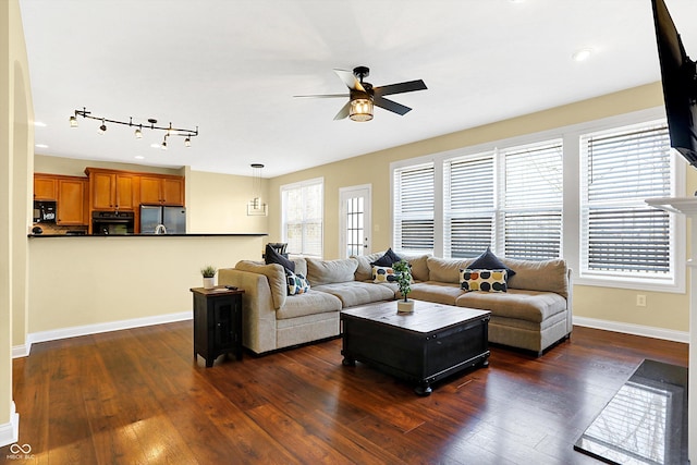 living room with dark wood-style flooring, a ceiling fan, and baseboards