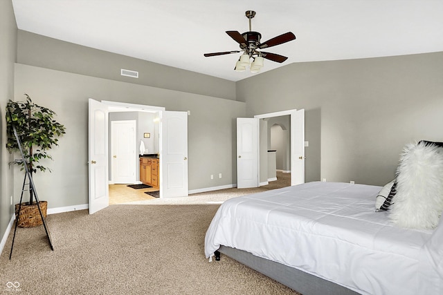 bedroom featuring light carpet, baseboards, visible vents, connected bathroom, and vaulted ceiling