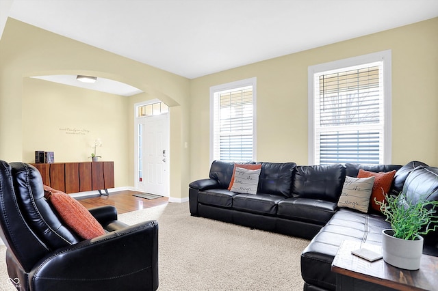 living room with carpet floors, arched walkways, plenty of natural light, and baseboards