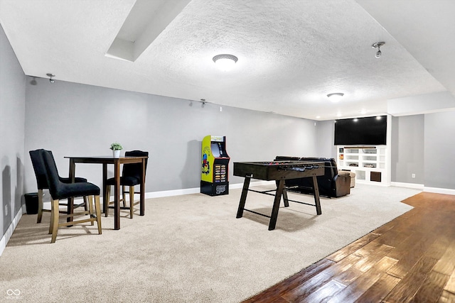 playroom with a textured ceiling, wood finished floors, and baseboards