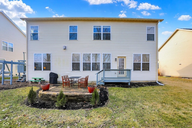 rear view of property featuring a wooden deck, a patio, and a yard