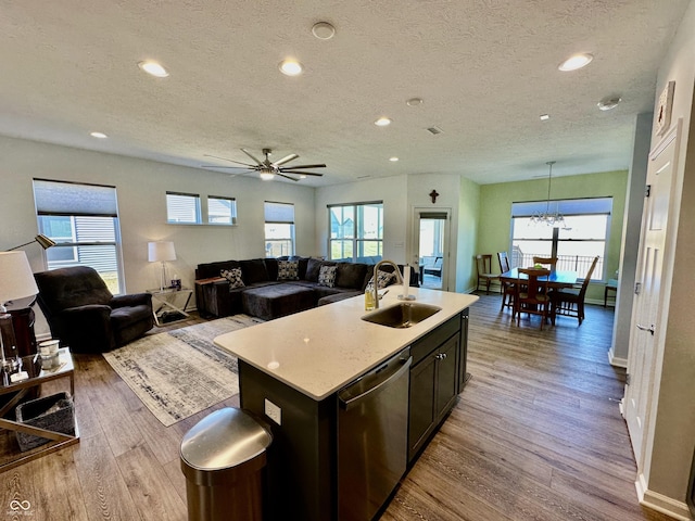 kitchen featuring light countertops, open floor plan, a sink, wood finished floors, and dishwasher