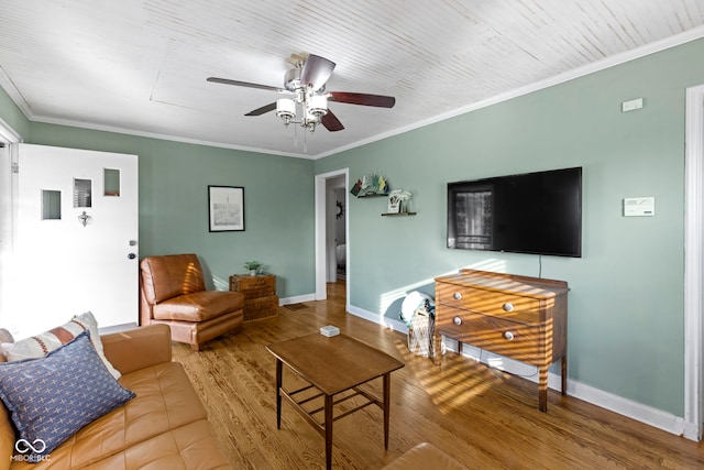 living room featuring ceiling fan, crown molding, baseboards, and wood finished floors