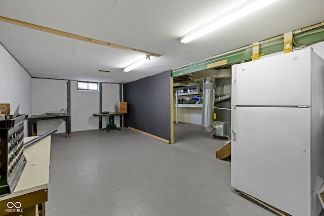 below grade area with freestanding refrigerator and concrete block wall