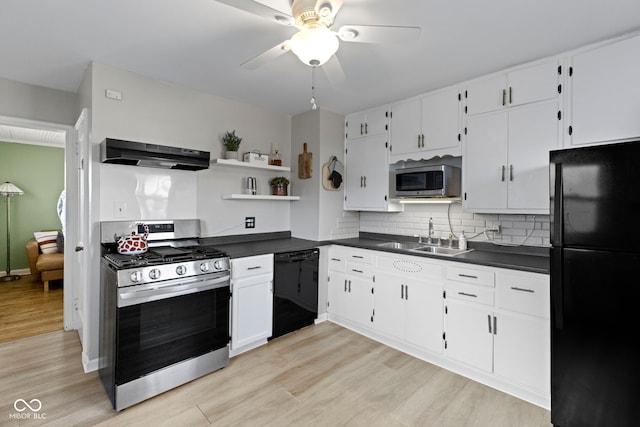 kitchen with dark countertops, a sink, under cabinet range hood, and black appliances