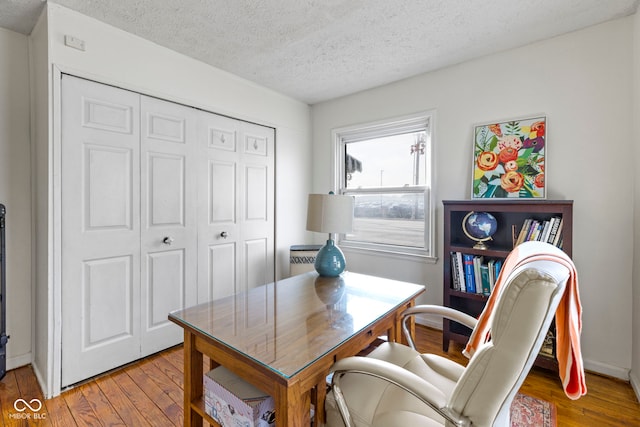 home office with a textured ceiling, wood finished floors, and baseboards