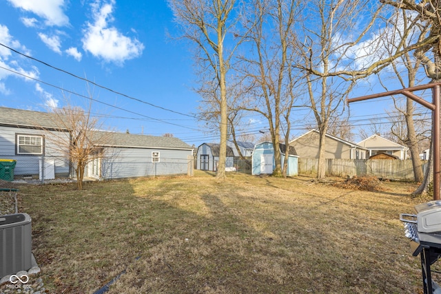 view of yard featuring central AC unit, a residential view, fence, a storage unit, and an outdoor structure