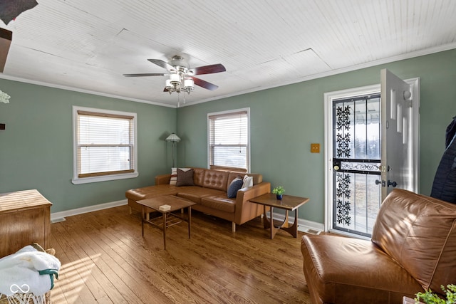 living area featuring baseboards, hardwood / wood-style flooring, and crown molding