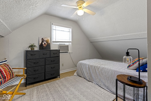 bedroom with baseboards, ceiling fan, wood finished floors, vaulted ceiling, and a textured ceiling