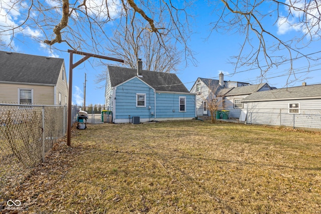 back of property featuring a lawn, a chimney, and a fenced backyard