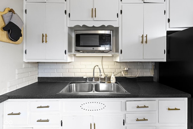 kitchen featuring stainless steel microwave, a sink, and white cabinetry