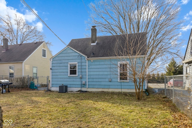 rear view of property featuring central AC, fence, a yard, roof with shingles, and a chimney