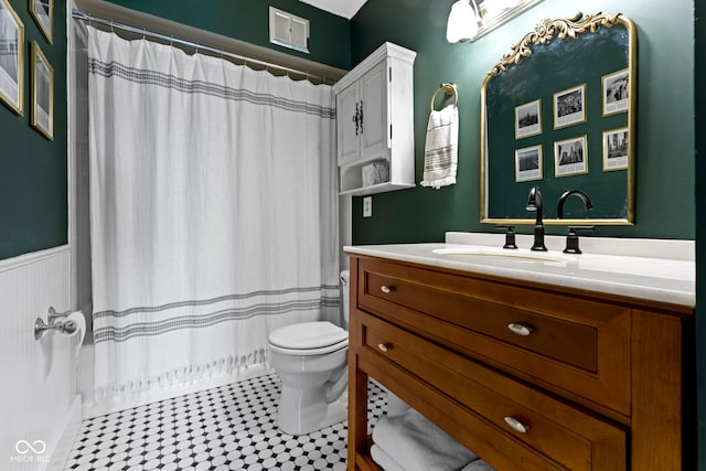 bathroom featuring visible vents, toilet, a wainscoted wall, curtained shower, and vanity