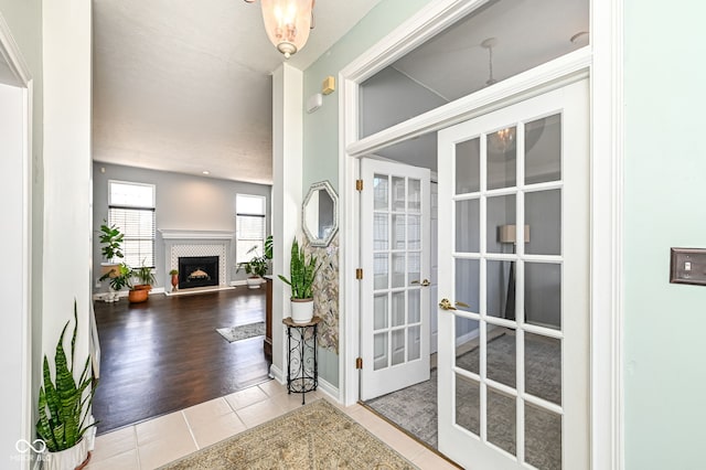 entryway with tile patterned flooring, french doors, a fireplace, and baseboards