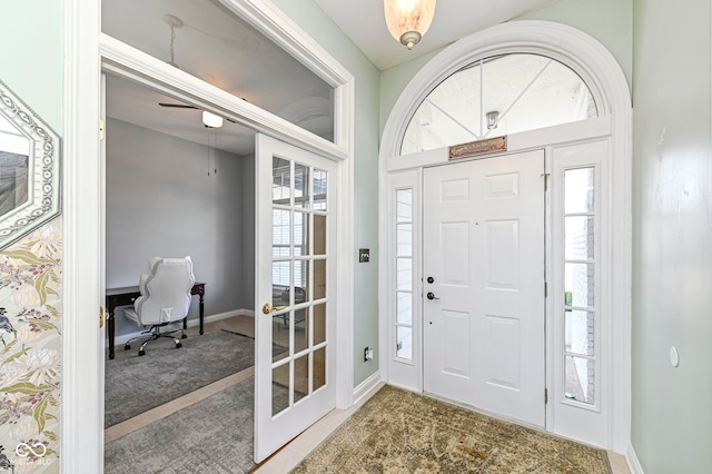 carpeted entrance foyer featuring baseboards, a wealth of natural light, and french doors