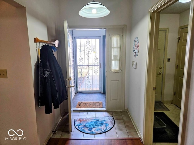 doorway to outside with tile patterned flooring and baseboards