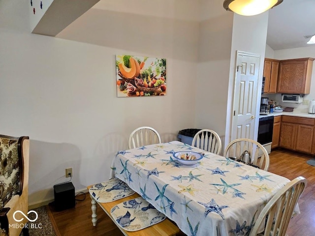 dining room featuring baseboards, vaulted ceiling, and light wood finished floors