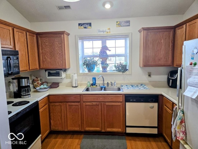 kitchen with electric range oven, a sink, visible vents, freestanding refrigerator, and dishwasher