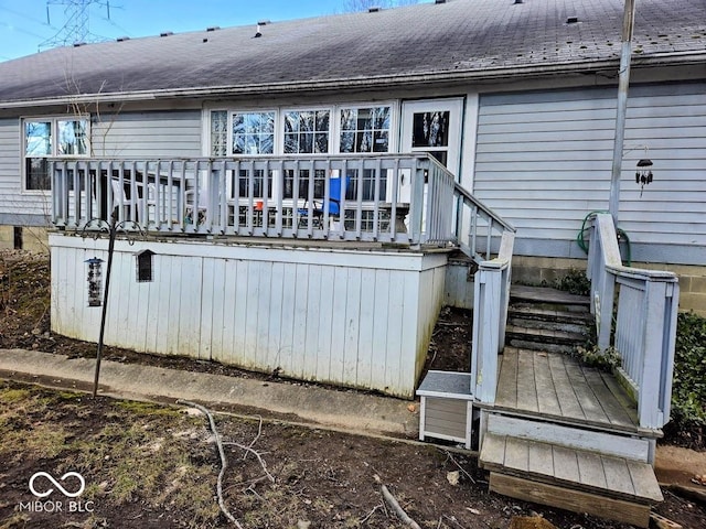 back of property featuring a shingled roof and a wooden deck