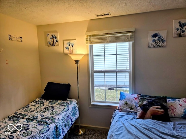 bedroom with visible vents, a textured ceiling, and baseboards