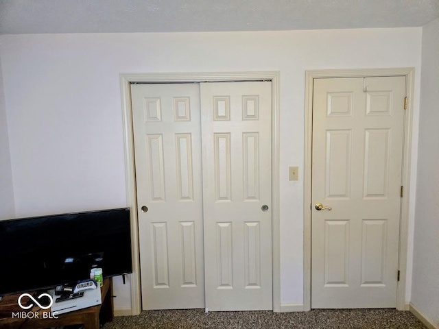 interior space featuring dark colored carpet, a closet, and baseboards