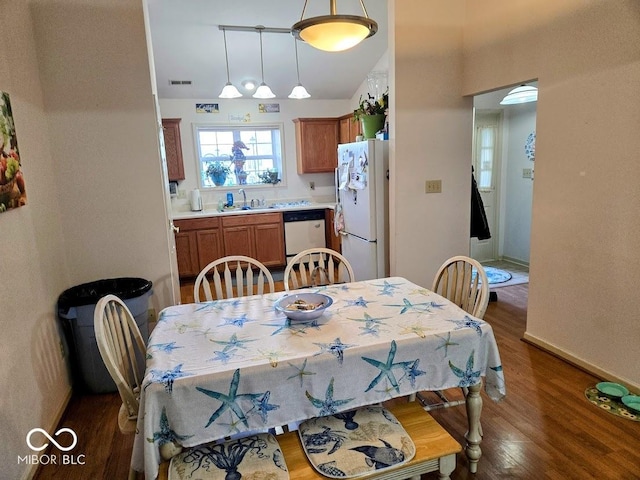 dining space with baseboards, visible vents, vaulted ceiling, and wood finished floors