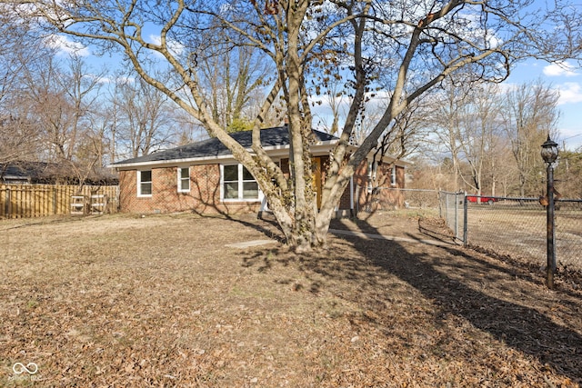 rear view of property with a gate, brick siding, and fence