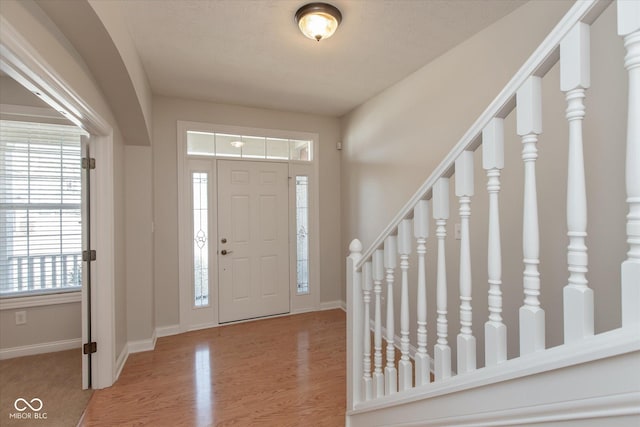 foyer entrance featuring stairs, wood finished floors, and baseboards