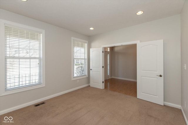 unfurnished bedroom with recessed lighting, multiple windows, visible vents, and carpet flooring