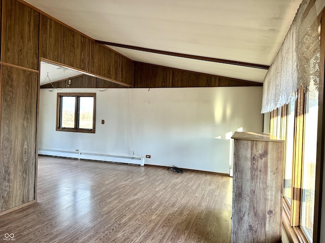 spare room featuring wooden walls, wood finished floors, lofted ceiling with beams, and a baseboard radiator