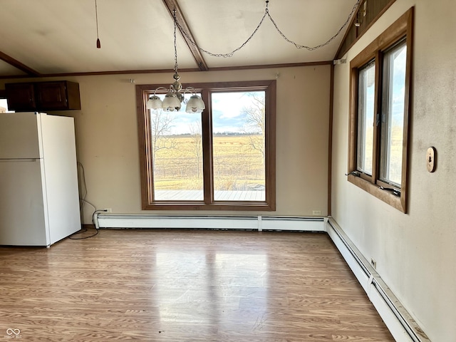 unfurnished dining area with light wood-type flooring, a baseboard heating unit, and a wealth of natural light