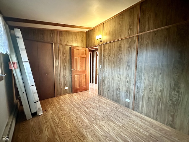 unfurnished bedroom with a closet, wooden walls, and wood finished floors