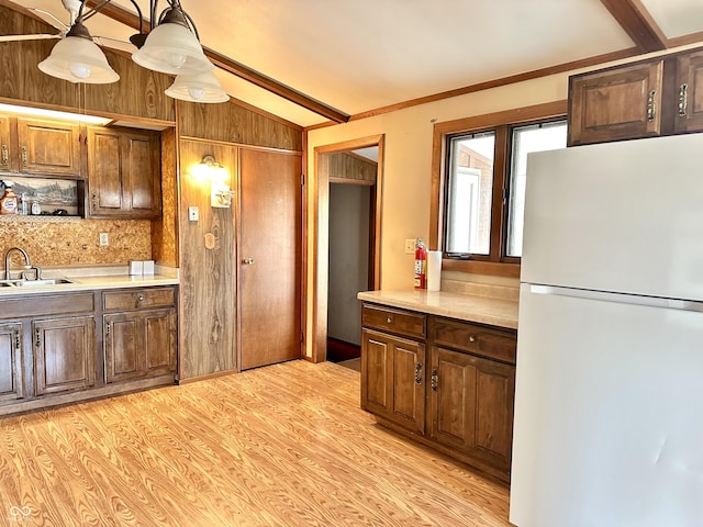 kitchen featuring light wood-style flooring, light countertops, freestanding refrigerator, and a sink