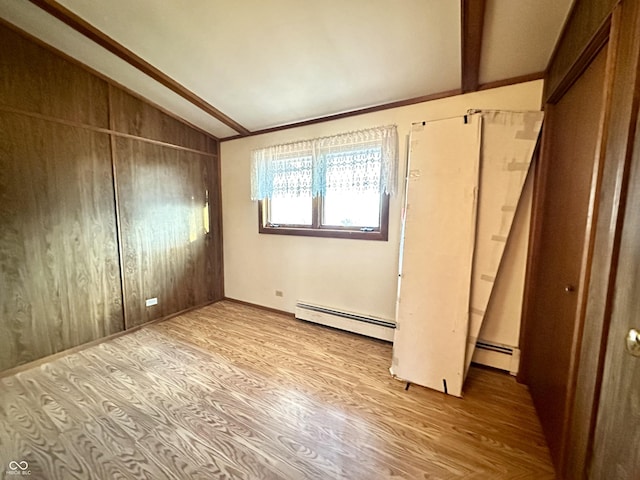 unfurnished room featuring lofted ceiling with beams, a baseboard radiator, and light wood-style flooring