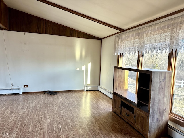 spare room with baseboard heating, wood finished floors, and vaulted ceiling