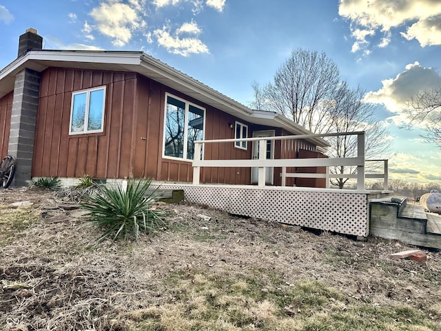 view of home's exterior with a wooden deck, a chimney, board and batten siding, and crawl space