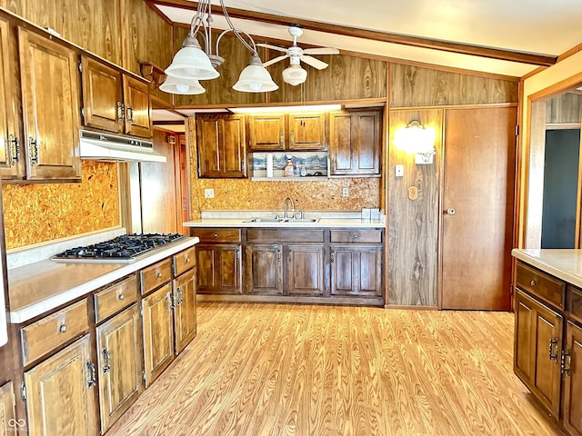 kitchen with under cabinet range hood, vaulted ceiling with beams, light countertops, and a sink