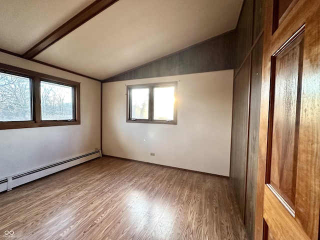 spare room featuring lofted ceiling with beams, a baseboard heating unit, and light wood-style floors