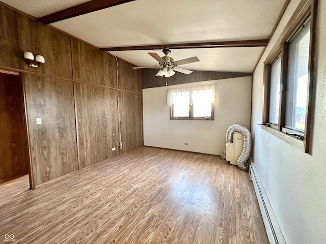 empty room featuring wooden walls, vaulted ceiling with beams, ceiling fan, baseboard heating, and wood finished floors