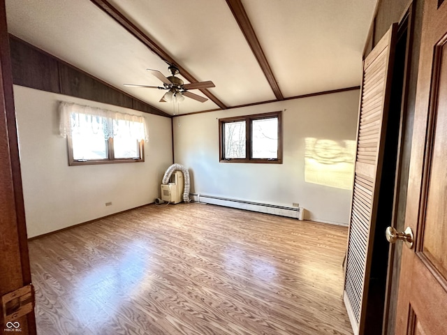 unfurnished room featuring a wealth of natural light, baseboard heating, lofted ceiling with beams, and wood finished floors