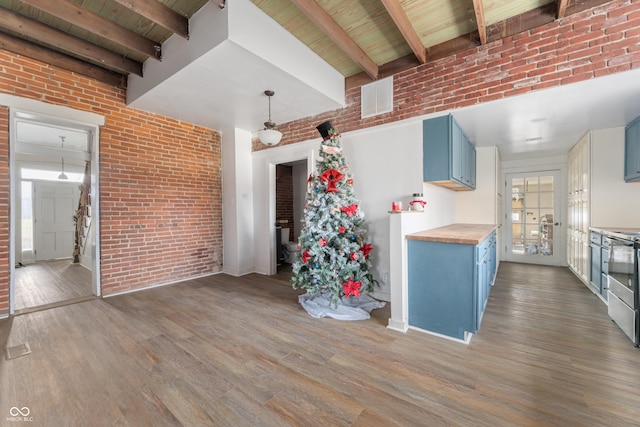 kitchen featuring blue cabinets, wooden counters, and brick wall