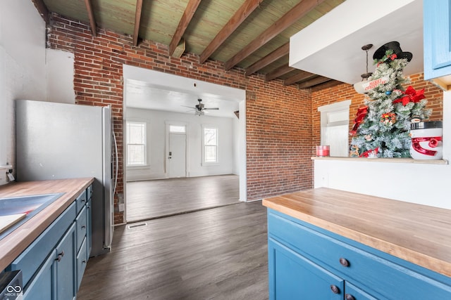 kitchen with blue cabinets, beamed ceiling, and brick wall