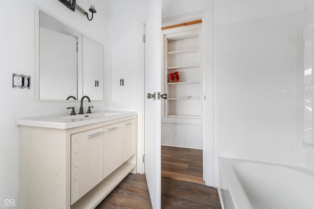 full bath with a bathing tub, built in features, wood finished floors, and vanity