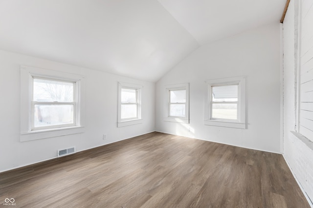 unfurnished room featuring vaulted ceiling, wood finished floors, and visible vents