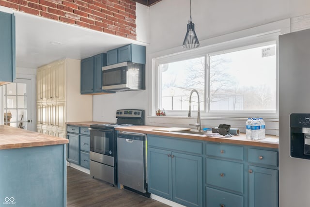 kitchen with stainless steel appliances, butcher block counters, and blue cabinetry
