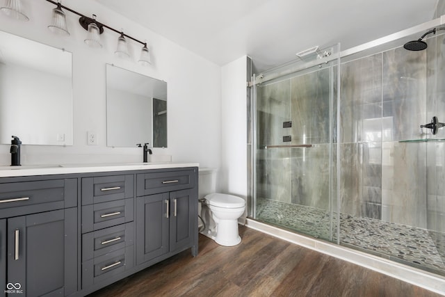 bathroom featuring wood finished floors, a stall shower, a sink, and toilet