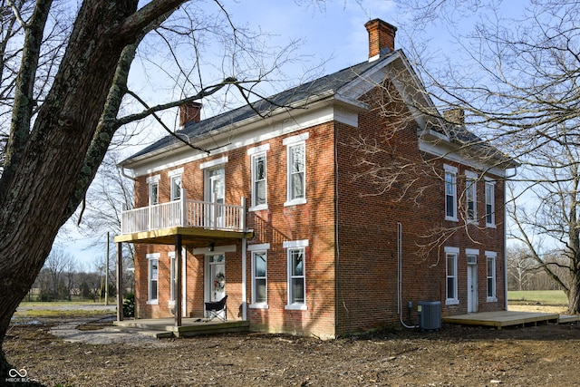 exterior space featuring a chimney, central AC unit, and brick siding